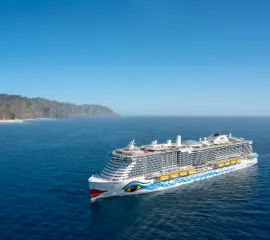 Außenansicht von AIDAnova auf See vor einer Bergkette