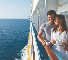 Außenbereich auf einem Schiff der Costa Flotte in der Abenddämmerung. An der gläsernen Reling laden einige gemütliche Liegestühle zum Verweilen ein.