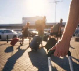 Alle Fragen und Antworten zur Anreise und Abreise bei Hapag-Lloyd Cruises. Auf dem Bild: Personen mit Koffern auf dem Weg zum Hafen.