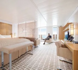 Ein Mann sitzt auf einem Sessel in der Penthouse Suite auf der MS Europa 2 von Hapag-Lloyd Cruises.