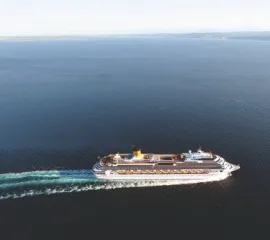 Die Costa Favolosa aus einem weiten Winkel und von oben fotografiert fährt von links nach rechts und hinterlässt eine Spur im Ozean.