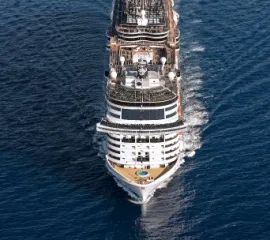 Die MSC Bellissima von oben herab fotografiert auf offener See. Durch die Frontansicht sind die verschiedenen Decks und das Entertainment erkennbar.