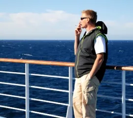 Rauchender Mann im Außenbereich eines Kreuzfahrtschiffes.
