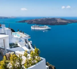 Kreuzfahrtschiff auf dem Meer vor den weißen Häusern von Santorini.