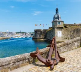 Französisches Dorf mit Festung in Wassernähe und großem Anker.