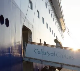 Das Logo von Celestyal Cruises mit einem sonnenähnlichen Emblem auf blauem Grund.