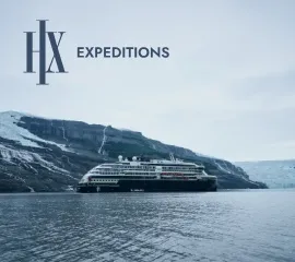 Ein Schiff von HX Expeditions gleitet im kalten Polarwasser entlang einer Felsformation. Oben links in der Ecke ist das Logo eingebettet.
