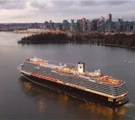 Ein Holland America Schiff auf dem Meer vor einer Großstadt.