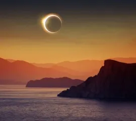 Eine totale Sonnenfinsternis über dem Meer und Felsen.