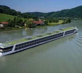 Die Emerald Astra auf einem ruhigen Fluss neben einem Ufer.