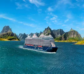 Das neue InTUItion-Klasse Kreuzfahrtschiff <i>Mein Schiff Relax</i> von TUI Cruises navigiert durch eine malerische Fjordlandschaft unter strahlend blauem Himmel.