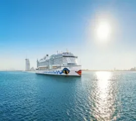 Das Schiff AIDAprima im Wasser und Dubai im Hintergrund.
