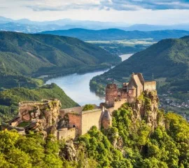 Die Burgruine Aggstein in Österreich auf der Spitze eines Bergs mit perfektem Blick auf die kurvige Donau bei gutem Wetter.