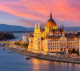 Das beeindruckende Parlament in Budapest direkt an der Donau in einem Sonnenuntergang.