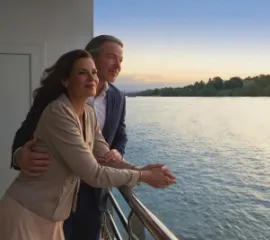 Ein Pärchen steht an der Reling eines AMADEUS Schiffs und schaut auf die vorbeiziehende Landschaft.