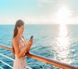 Frau nutzt Smartphone auf AIDA Kreuzfahrt an Deck bei Sonnenuntergang für die gratis Internet-Flat 2026.