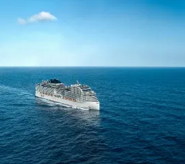 Die MSC World America gleitet im tiefblauen Wasser. Im Hintergrund gibt es Wolken.