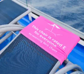 Ein Liegestuhl an Deck eines Kreufzarhtschiffes, auf dem steht, dass der Stuhl allen zur Benutzung freisteht.