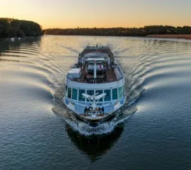 Die Ms Rousse Prestige auf einem ruhigen Fluss im Sonnenuntergang fährt auf die Kamera zu.