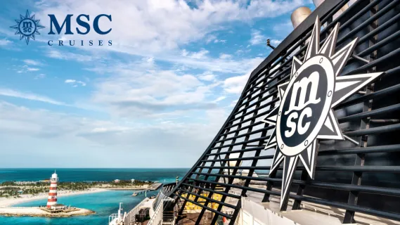 Schornstein eines MSC Cruises Schiffs mit dem MSC-Logo und Blick auf den rot-weiß gestreiften Leuchtturm der Privatinsel Ocean Cay.