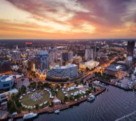 Luftaufnahme von Downtown Norfolk in Virginia bei Sonnenuntergang mit dem Town Point Park am Elizabeth River nahe dem Kreuzfahrthafen.
