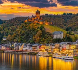 Die historische Reichsburg Cochem überragt malerisch die Moselpromenade bei Sonnenuntergang.