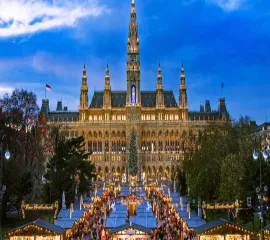 Der stimmungsvolle Wiener Christkindlmarkt mit glitzernden Lichtern vor der monumentalen Kulisse des neugotischen Rathauses, ideal für einen Landausflug auf eigene Faust.