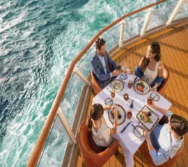 EIne Gruppe Reisender auf einem Schiff von NCL, die ausgelassen zu Abend essen.