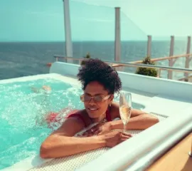 Eine Frau entspannt mit einem Sekt im Whirlpool  - Sie hat im Premium-Preis von Cunard gebucht.