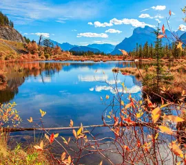 Herbstlich leuchtende Indian-Summer-Landschaft Nordamerikas mit rot-goldenen Wäldern und Bergspiegelung im See auf einer Expedition von Hapag-Lloyd Cruises.