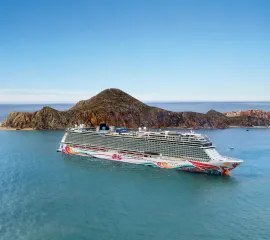 Norwegian Joy an der mexikanischen Reviera im Meer mit einer Felsformation im Hintergrund.