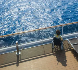 Eine Frau im Rollstuhl an Deck eines Kreuzfahrtschiffes.