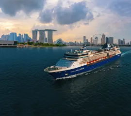 Die Celebrity Millennium von Celebrity Cruises fährt von einer asiatischen Großstadt ab.