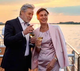 Elegantes Paar genießt Wein bei Sonnenuntergang auf dem Sonnendeck einer AMADEUS Flusskreuzfahrt 2027.