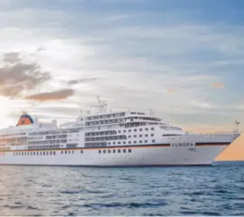 Die MS EUROPA auf hoher See im Sonnenaufgang.