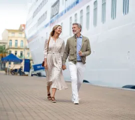 Ein Pärchen in sportlich-legerer Kleidung geht nach einem Landausflug zurück auf das Hapag-Lloyd Schiff.