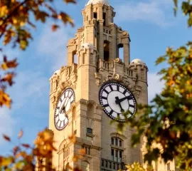 Ein Turm mit einer Uhr, eingerahmt von herbstlichen Blättern. Symbolbild: Zeitlich begrenzte Aktionen für Ihre Kreuzfahrt-Buchung.