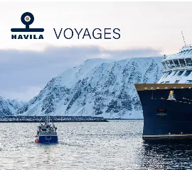 Das moderne Hybridschiff Havila Castor von Havila Voyages liegt im winterlichen Fjordhafen vor schneebedeckten Bergen.