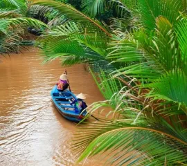 Eine alte Dame in einem kleinen Paddelboot auf dem Mekong.