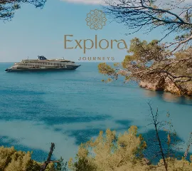 Luxusschiff von Explora Journeys vor einer malerischen Küstenkulisse im Azurblauen Meer.