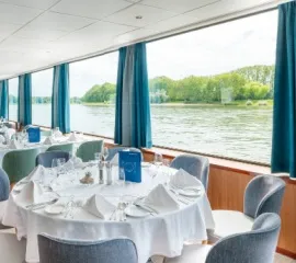 Ein Restaurant mit Panorama-Fenstern und runden Tischen auf der Rhein Melodie von nicko cruises.