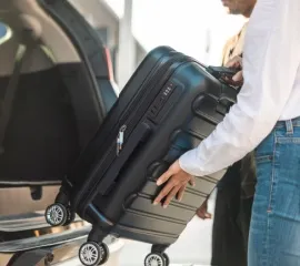 Koffer wird in den Kofferraum eines Autos geladen.