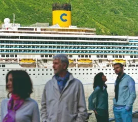 Vier Menschen an einem Hafen im Geirangerfjord. Im Hintergrund die Costa Fortuna, die sie über Ahoi-Schiff.de gebucht haben.