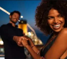 Ein Mann hält die Hand einer Frau beim Tanzen auf dem Deck bei Nacht.