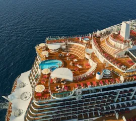 Außenbereich des Restaurants Brauhaus auf AIDAnova mit grünen Sonnenschirmen und Holzstühlen.