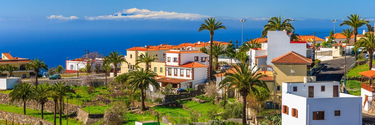 Ausblick von La Gomera: Teide am Horizont Malerisches Dorf auf La Gomera mit Palmen und spektakulärem Blick über das Meer auf den Vulkan Teide auf Teneriffa.