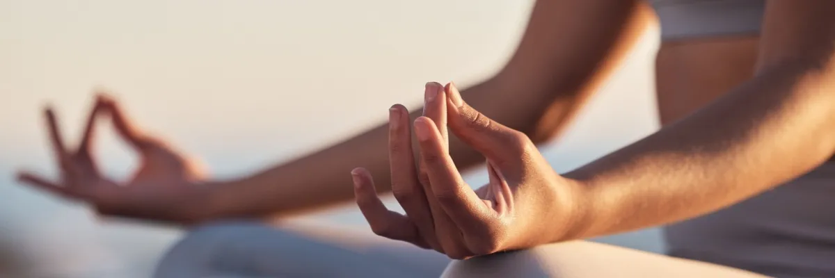Eine Frau in Sportklamotten sitz im Schneidersitz an Deck eines A-ROSA Schiffes und meditiert.