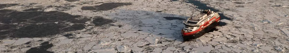 Ein Expeditionsschiff fährt durch Alaska. Im Hintergrund ist ein Gletscher.