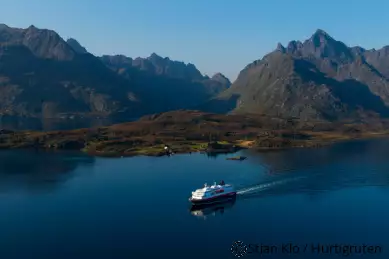 Kreuzfahrtschiff auf dem Wasser mit Bergen und Natur im Hintergrund