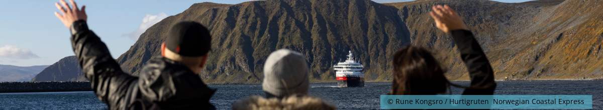 Drei Passagiere winken dem Kreuzfahrtschiff zu.